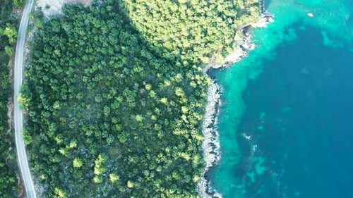Drohne fliegt über die Straße in der Nähe von Rocky Coast Line mit türkisem Meerwasser