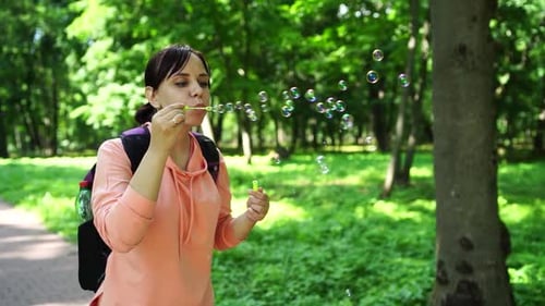 Junge Frau bläst Seifenblasen auf die Natur