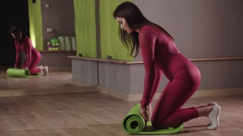Woman Unrolling Yoga Mat in Fitness Studio