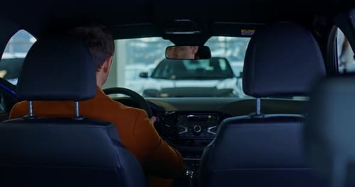 Man Sits in Car at Dealership