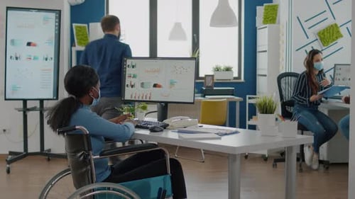 Travailleur noir paralysé et employé portant un masque de protection travaillant ensemble