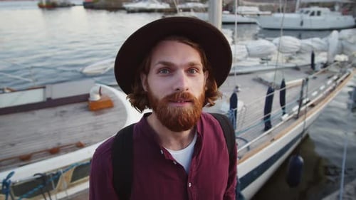 Homem ruivo sorridente em pé perto da baía