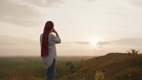 Woman Taking Photo on Hilltop at Sunset