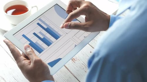 Rückansicht der Männerhand bei der Arbeit am digitalen Tablet am Schreibtisch,