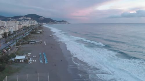 Coastline with pebble beach and promenade, people spending time on beach, relaxing
