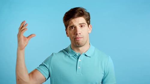 Handsome Bored Man Showing Bla-bla-bla Gesture with Hands and Rolling Eyes Isolated on Studio Blue