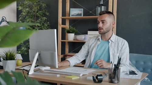 Young Professional Architect Studying Construction Plan Looking at Paper and Computer Screen Working
