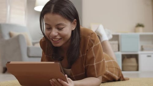 Young Woman Using Tablet While Lying on Floor