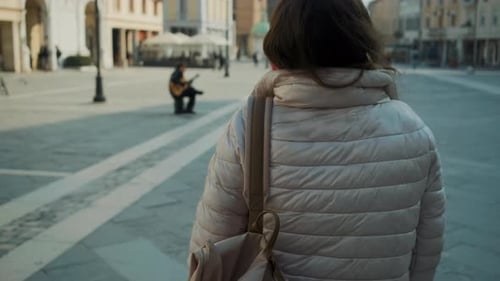 Dark Haired Lady Walks Along Large Square