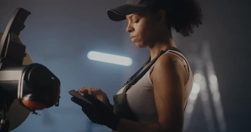 Ethnic Woman with Phone on Break in Factory Workshop