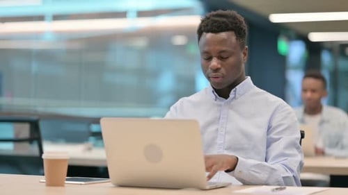 Young Adult Man Massaging Temples at Office Desk
