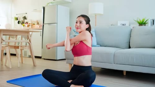 Woman Stretches Arms Doing Yoga in Home