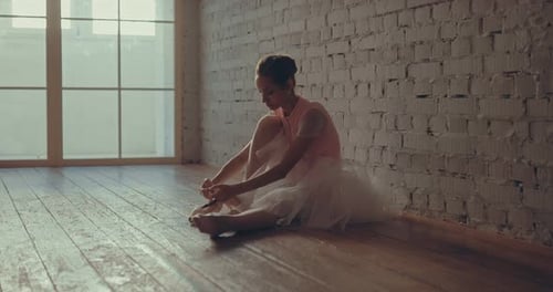 Ballet Dancer Putting On Pointe Shoes in Studio