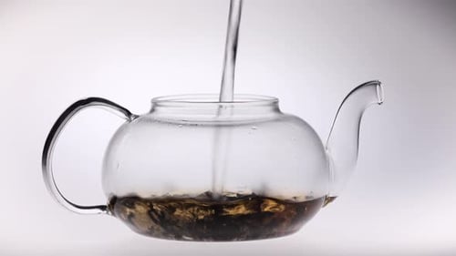 Water Pouring into Elegant Glass Teapot with Tea