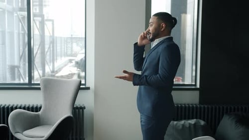 Slow Motion of Mixed Race Man in Suit Talking on Mobile Phone Walking in Modern Office