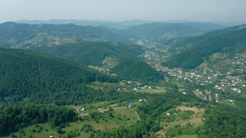 Aerial Drone View of a Village in a Mountain Valley Against a Blue Sky