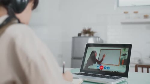 Asian little young girl learning online class from school teacher by digital remote internet at home
