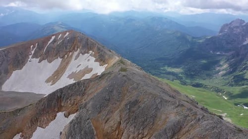 Aerial Shot of a Mountain Ridge Against Rocky Cliffs, Glacier and Snowy Peaks. Amazing Aerial View