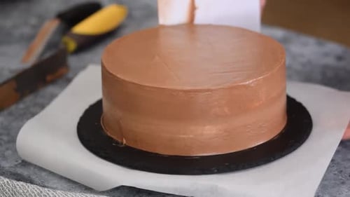 Chef Smoothing Chocolate Frosting on Delicious Cake