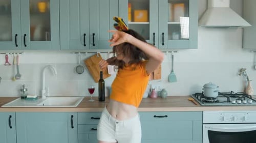 A Beautiful Woman in White Shorts is Relaxing at Home Dancing in the Kitchen
