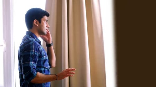 Man Talking on Cell Phone Indoors by Window