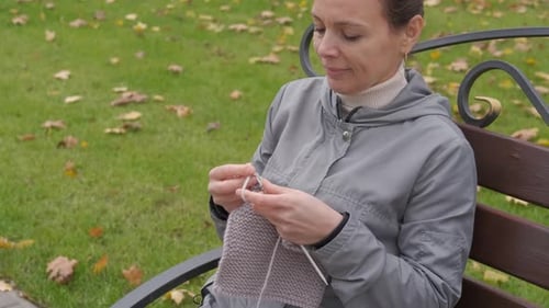 Sits with yarn in the park.