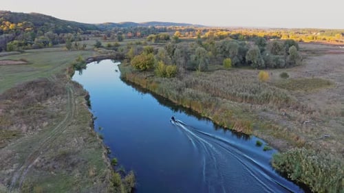 Small Motorboat Sails on Long Curvy River Running on Meadows