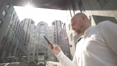 A Businessman Uses a Phone at Work Near a Business Center