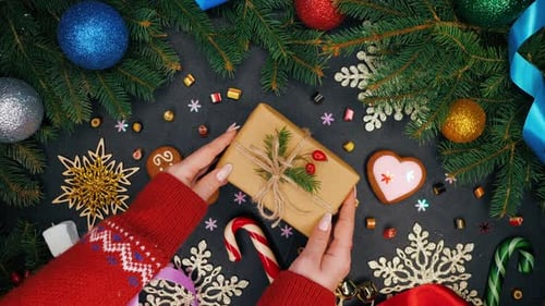 Woman's hands puts gift wrapped in craft paper on table and then takes it. Festive mood