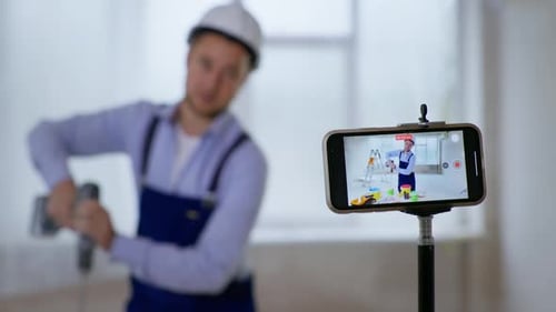 Male Painter Records Video for Blog on Smartphone and Mixes Paint in Bucket for Painting Walls