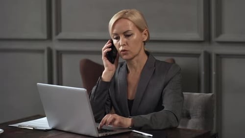 Professional Woman Working on Laptop and Talking on Phone