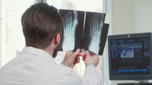 Rückansicht eines männlichen Arztes beim Blick auf Fußröntgenaufnahme eines Patienten