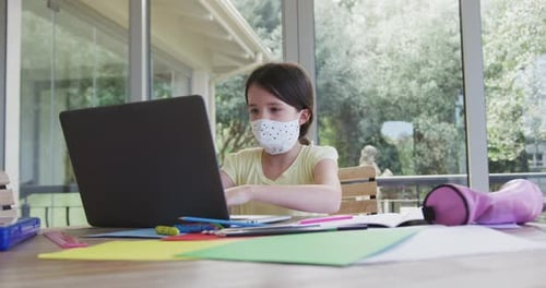 Girl in Mask Doing Schoolwork on Laptop