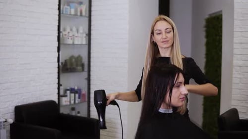 Cosmetologist Blow-Drying Client's Hair in Salon