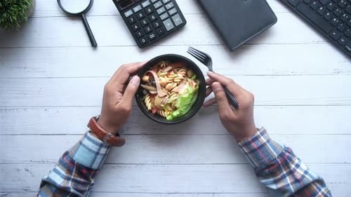 Men Eating Fresh Vegetable Salad in Bowl on Office Desk