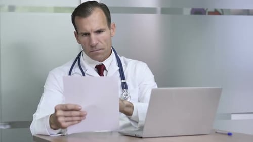 Doctor Working on Documetns and Laptop Medical Report