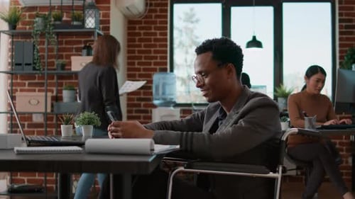 Man in Wheelchair Using Phone in Office