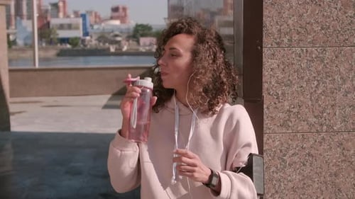 Tired Woman Sipping Water After Jogging