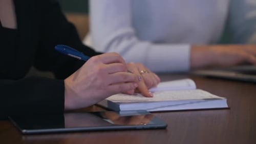 Woman Writing Notes During Business Meeting