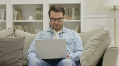 Young Adult Chatting on Laptop Video Call At Home
