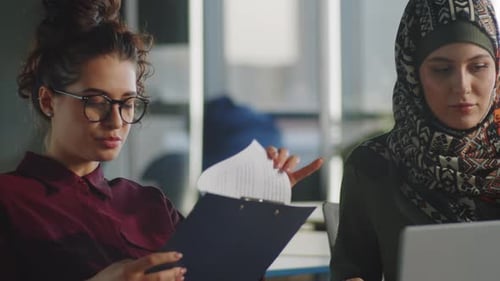 Office Meeting with Two Women Reviewing Documents