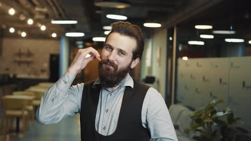 Man Combs His Beard in Modern Office