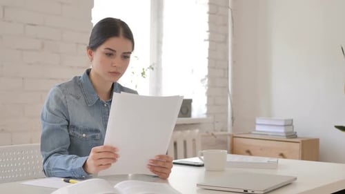 Young Adult Studying Documents at Home on Desk