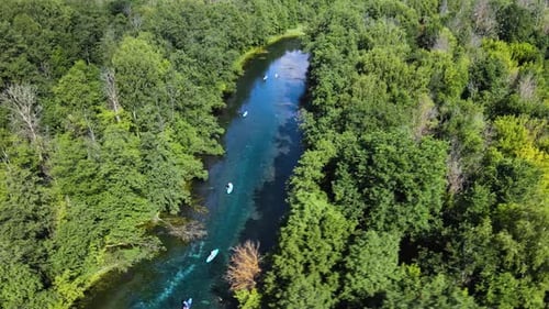 Tourists is paddling down the river on boards. Calm water of turquoise color