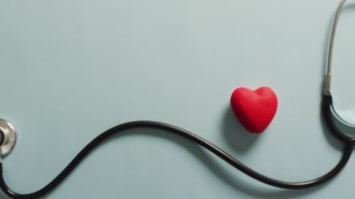 Video of close up of stethoscope with heart on blue background