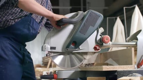Young Adult Cutting Wood with Compound Miter Saw