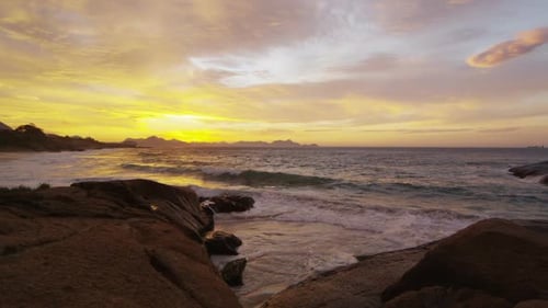 Gentle Waves on Rocky Shoreline at Sunset
