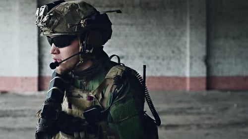 Soldat des forces spéciales marchant avec un fusil d'assaut ciblé dans un bâtiment détruit.