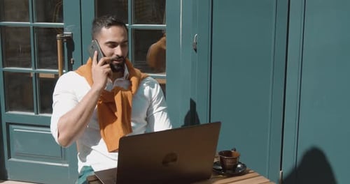 Man Working On Laptop While Talking On Phone