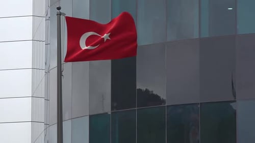 Turkish Flag Waving on Flagpole in Front of Modern Building